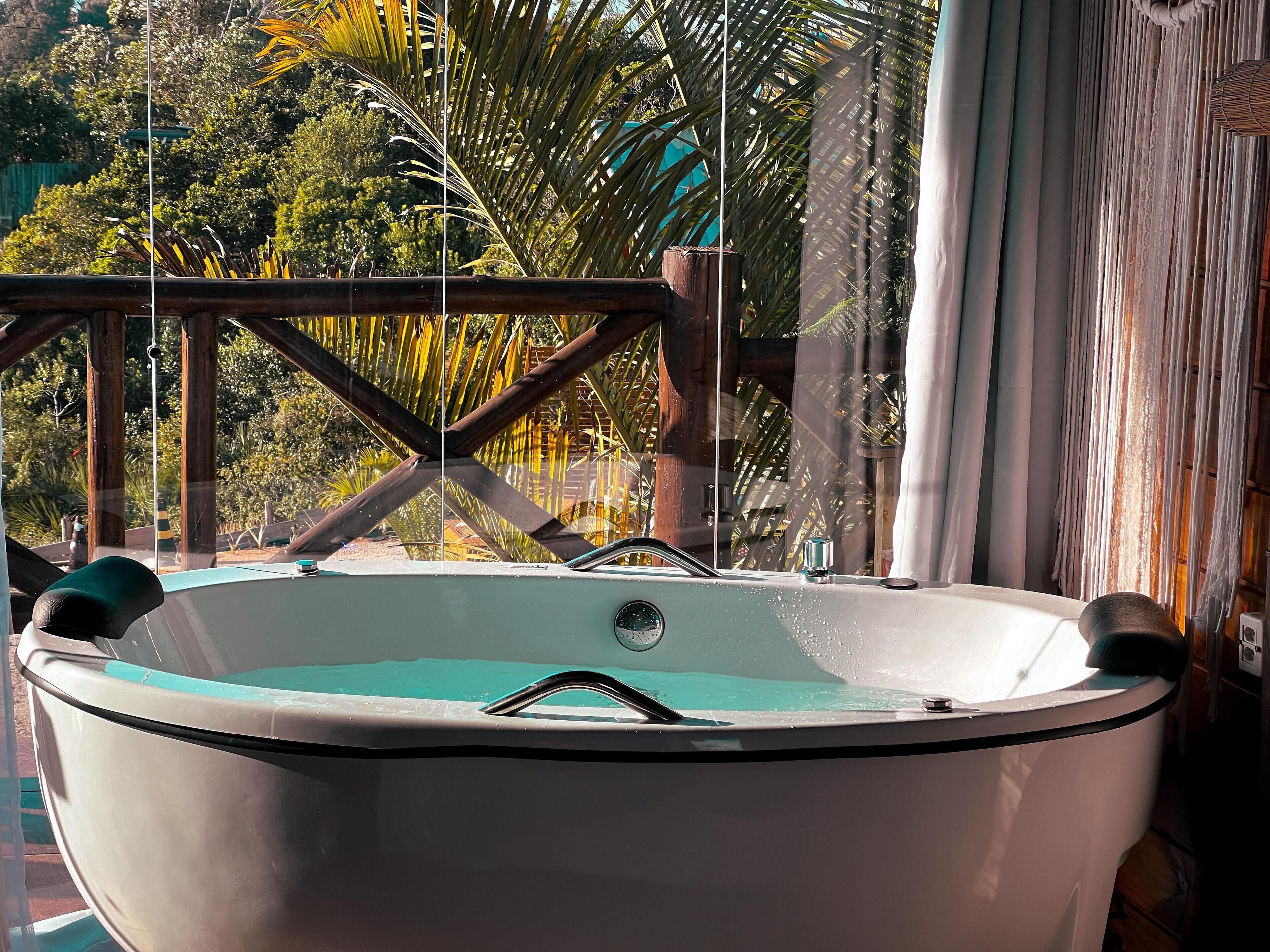 A hot tub with a wooden deck and a view of lush greenery.