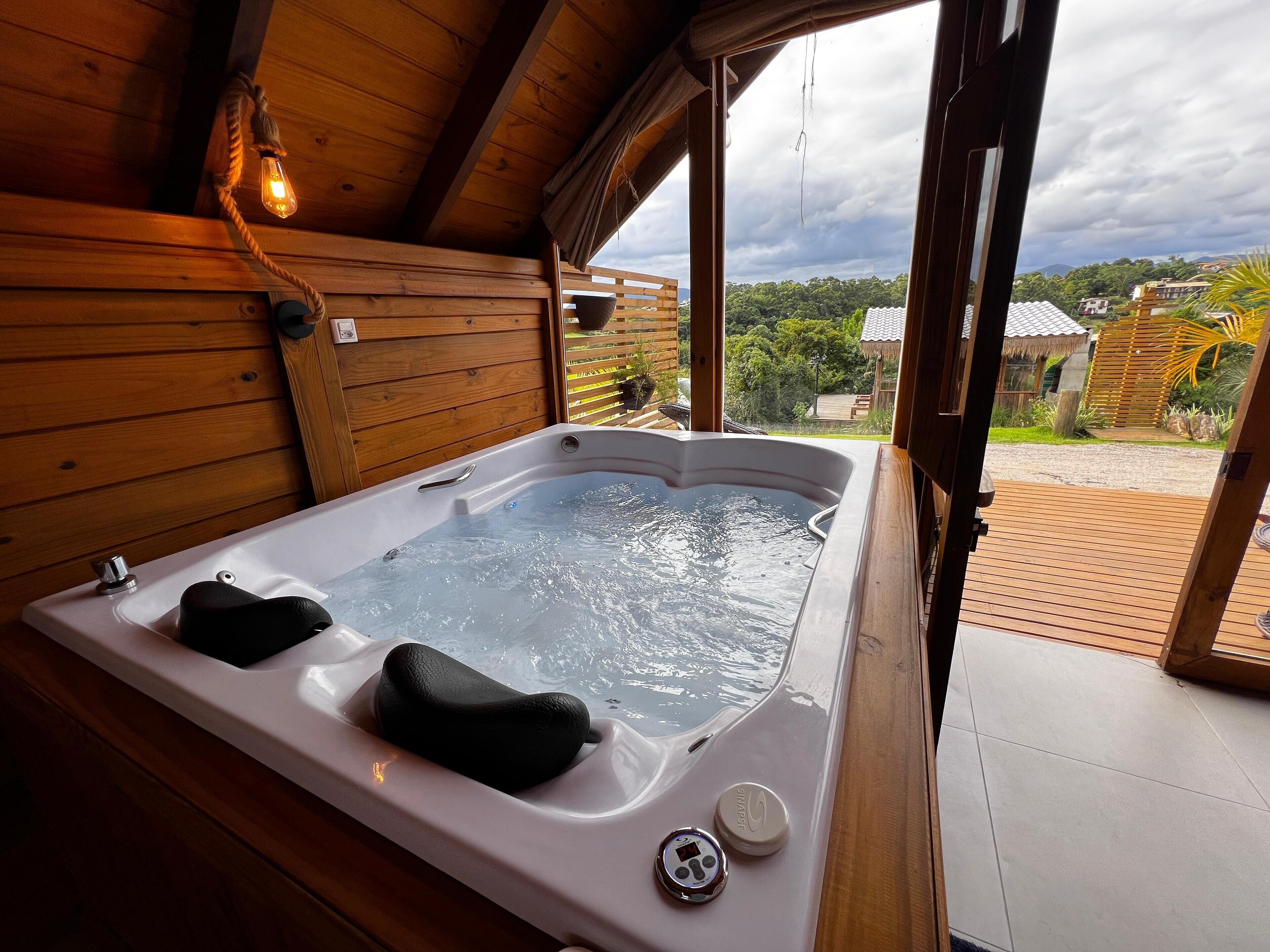 Una cabaña de madera con un jacuzzi, vistas del paisaje circundante y una terraza de madera.
