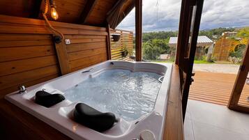 Una cabaña de madera con un jacuzzi, vistas del paisaje circundante y una terraza de madera.