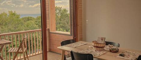 Un comedor con una mesa y sillas, vistas a la vegetación exterior y un techo de madera.