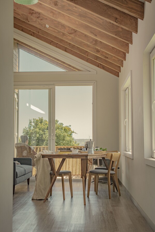 A modern kitchen with wooden beams, a large window, and a dining area with a table and chairs.