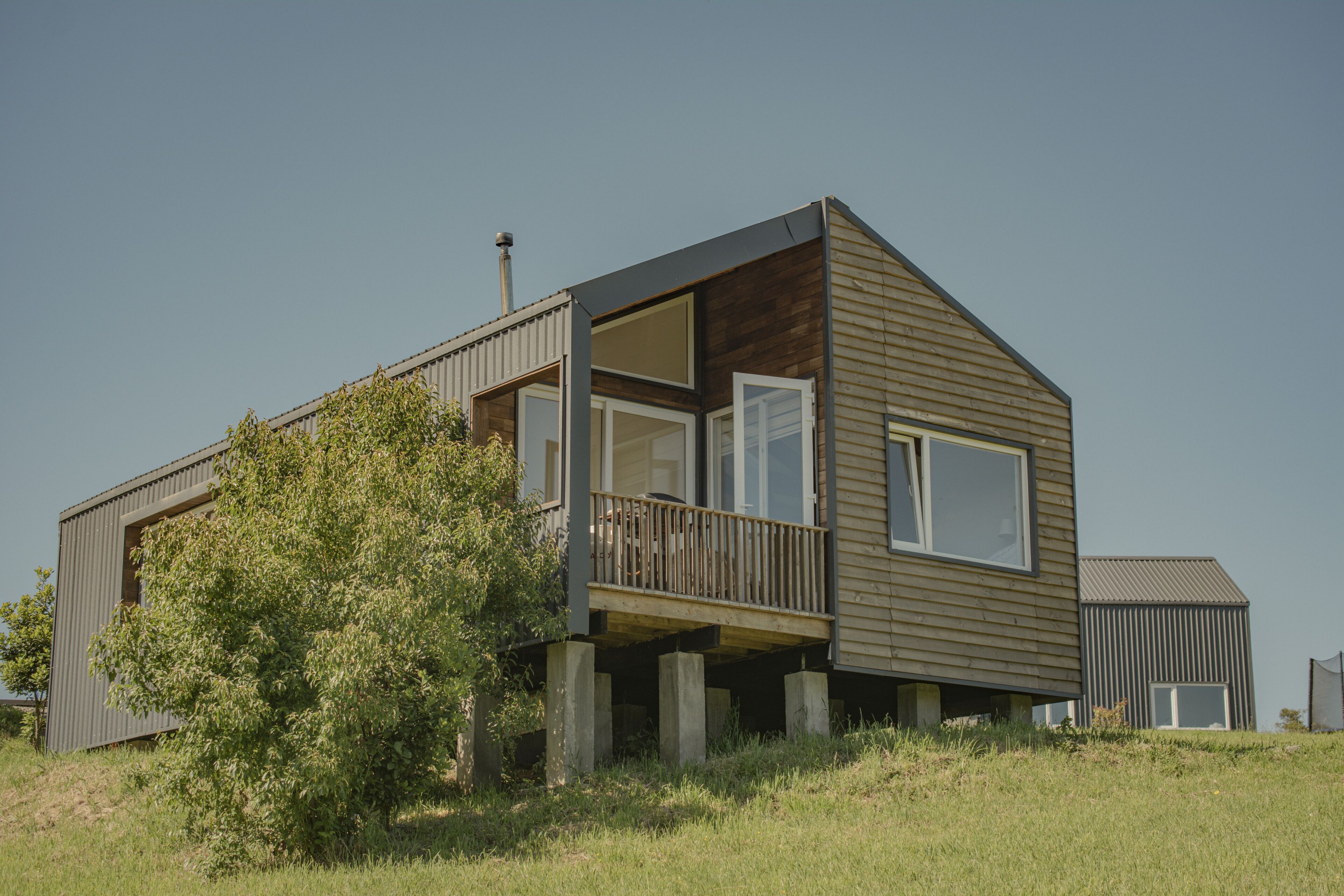 Een modern huis met twee verdiepingen, een balkon, grote ramen en een schoorsteen.