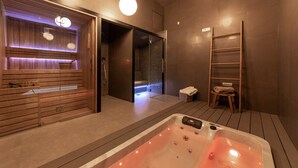 Un moderno cuarto de spa con sauna de madera, zona de ducha con cerramiento de vidrio y escalera de madera.