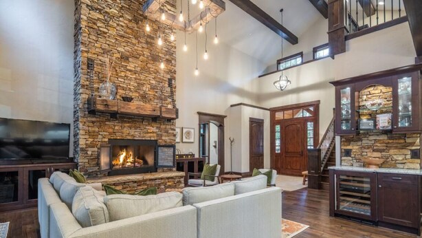 A spacious living room with a stone fireplace, a large sofa, and wooden flooring.