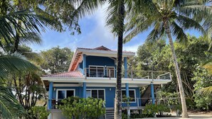 Una casa de dos pisos con fachada azul, techo rojo y un balcón.