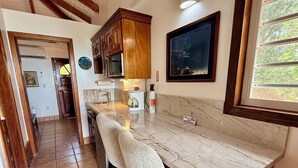 Una cocina con encimera de mármol, armarios de madera y un cuadro de un pez en la pared.