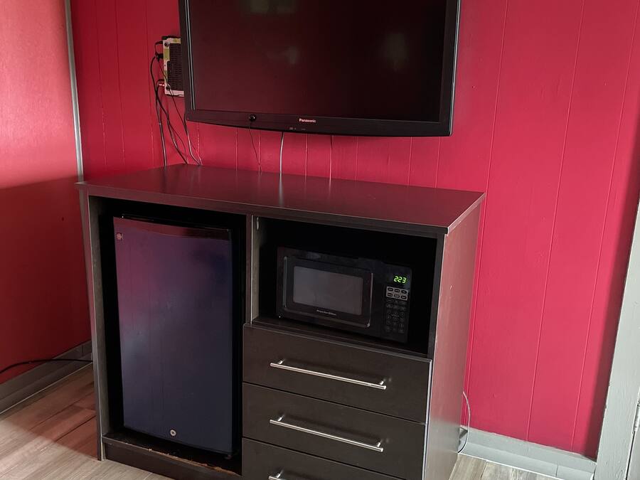 A kitchenette with a microwave, a small refrigerator, and a flat-screen TV mounted above the counter.