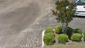A motel with a large parking lot and a row of rooms with a green roof. - BUDGETINN (Monroeville)