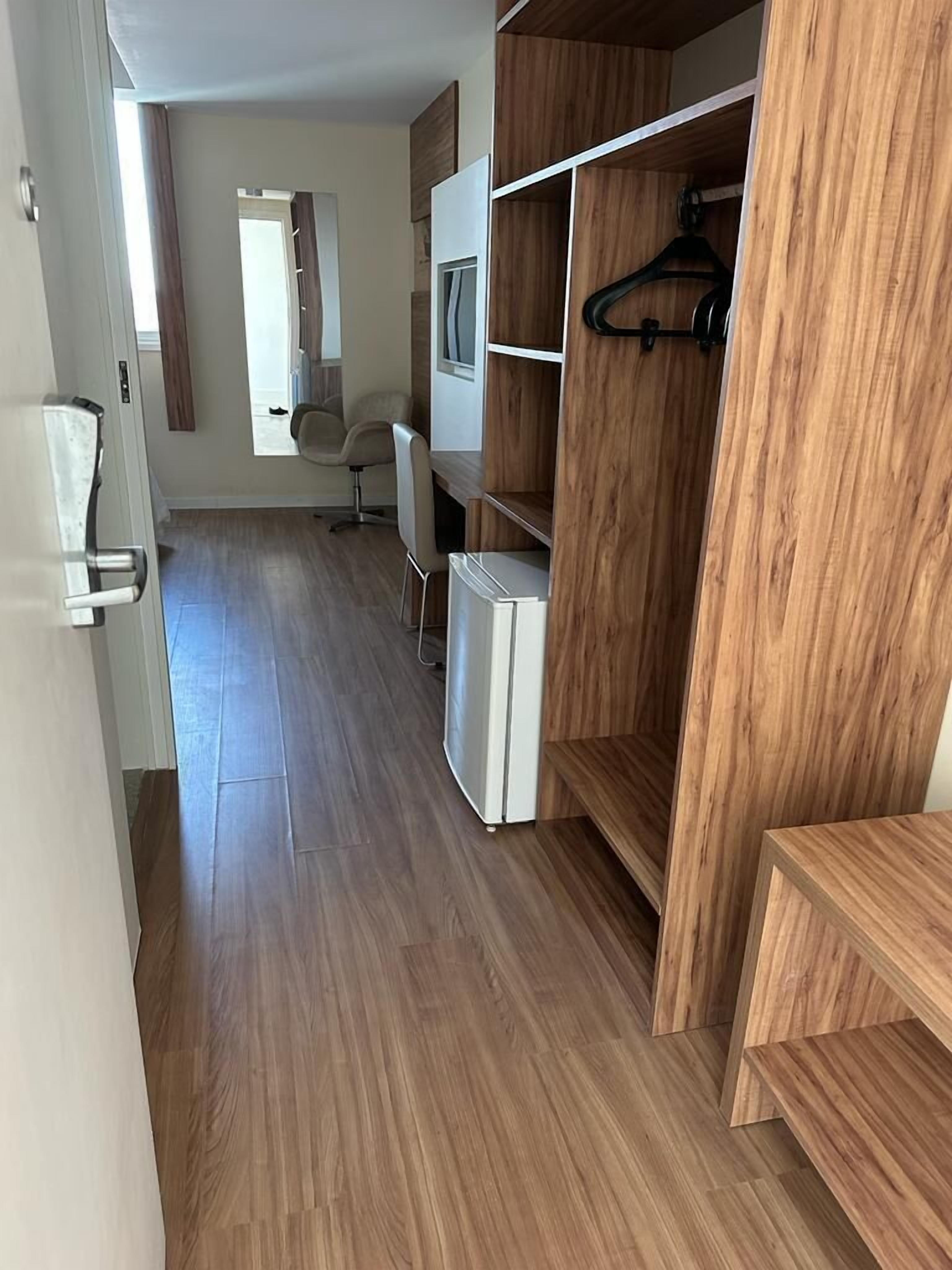 A modern room with a wooden floor, a white wardrobe, a small white desk, and a chair.