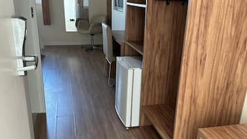A modern room with a wooden floor, a white wardrobe, a small white desk, and a chair.