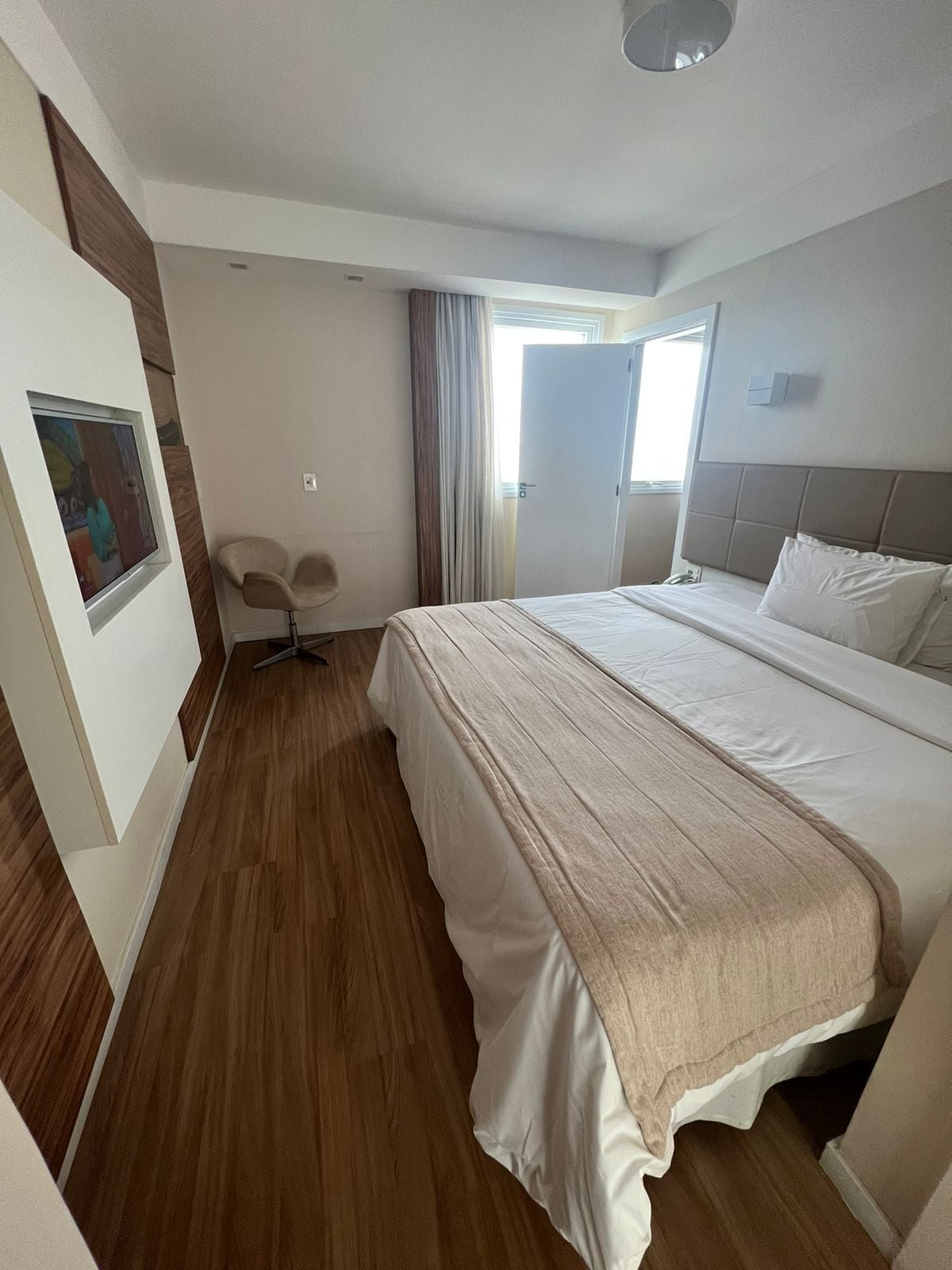 A modern hotel room with a large bed, a desk, and a chair.