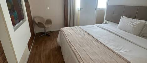 A modern hotel room with a large bed, a desk, and a chair.
