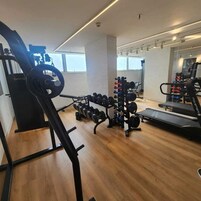 Academia com equipamentos de cardio, estação de musculação e esteira.
