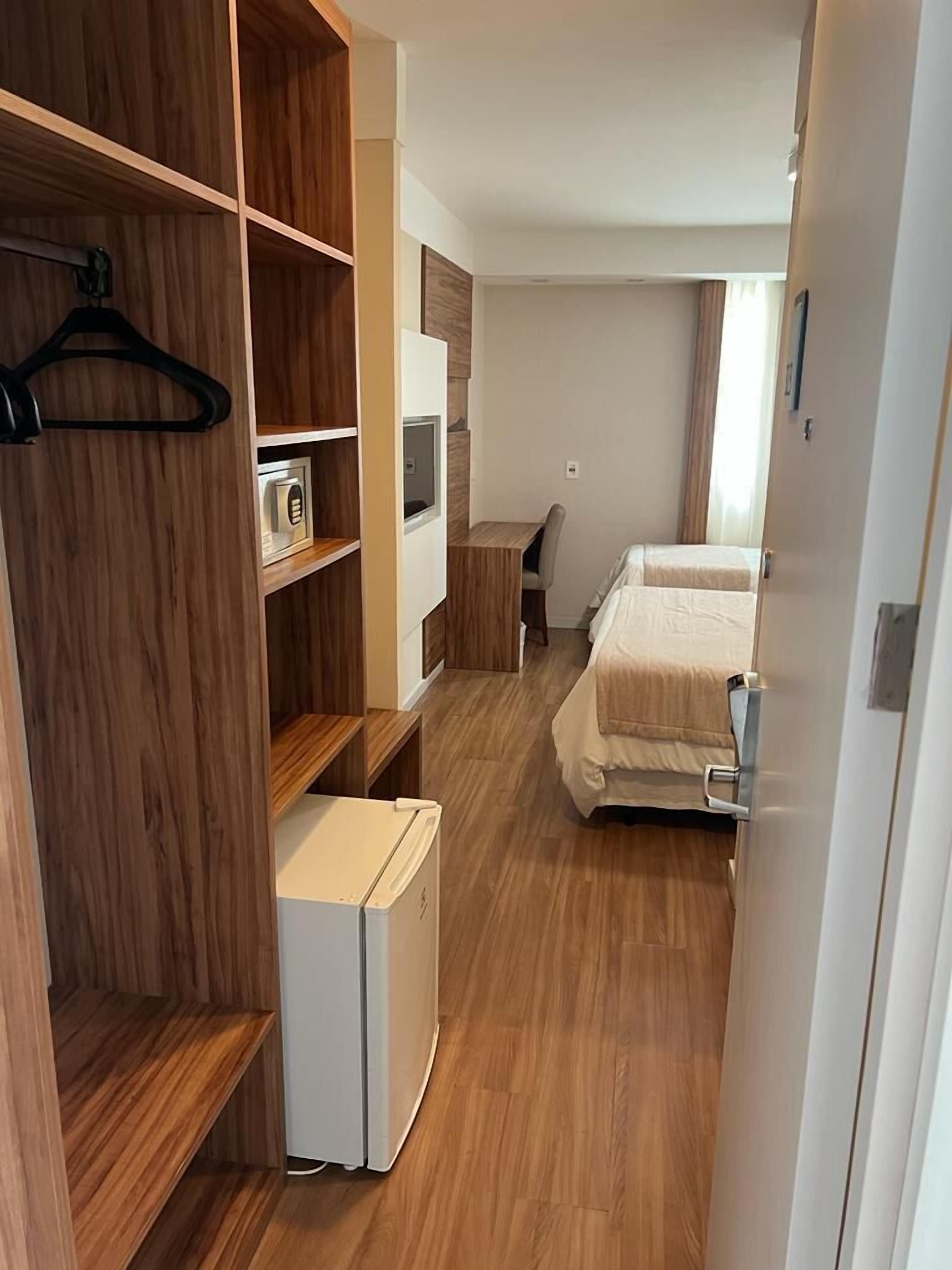 Una habitación compacta con kitchenette, cama, escritorio y armario.