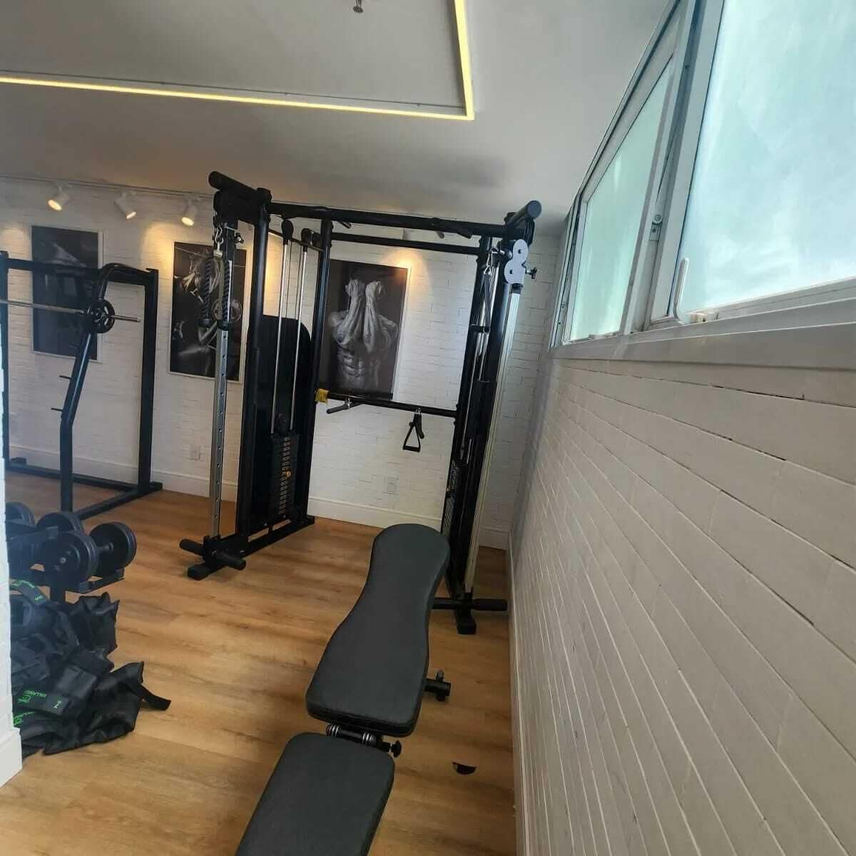 Een sportschool met een bank, een rek voor gewichten en trainingsapparatuur.