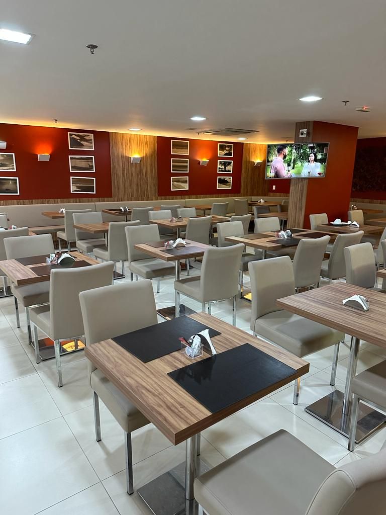 Un restaurante con varias mesas y sillas, una pantalla de televisión y marcos de cuadros en la pared.