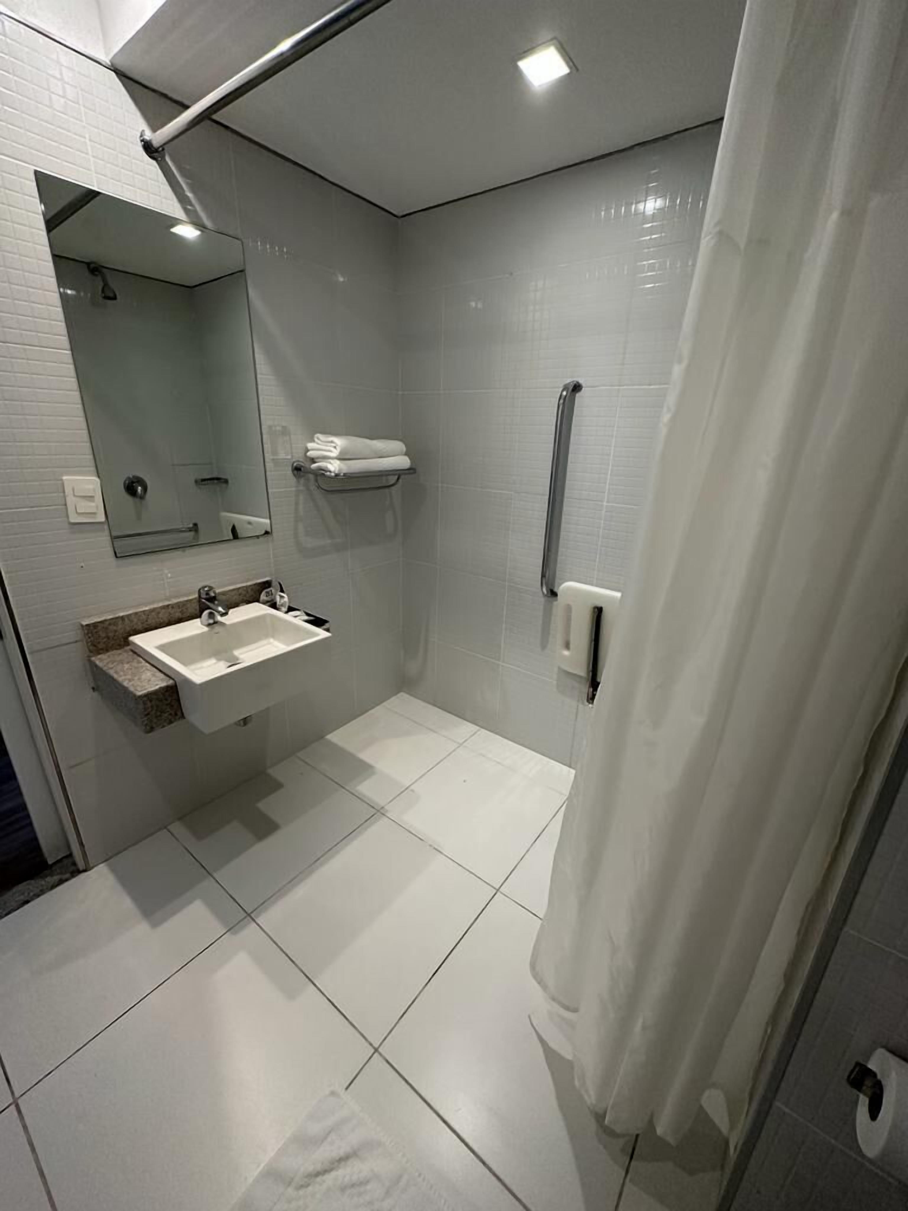 A modern bathroom with a sink, mirror, and shower area.