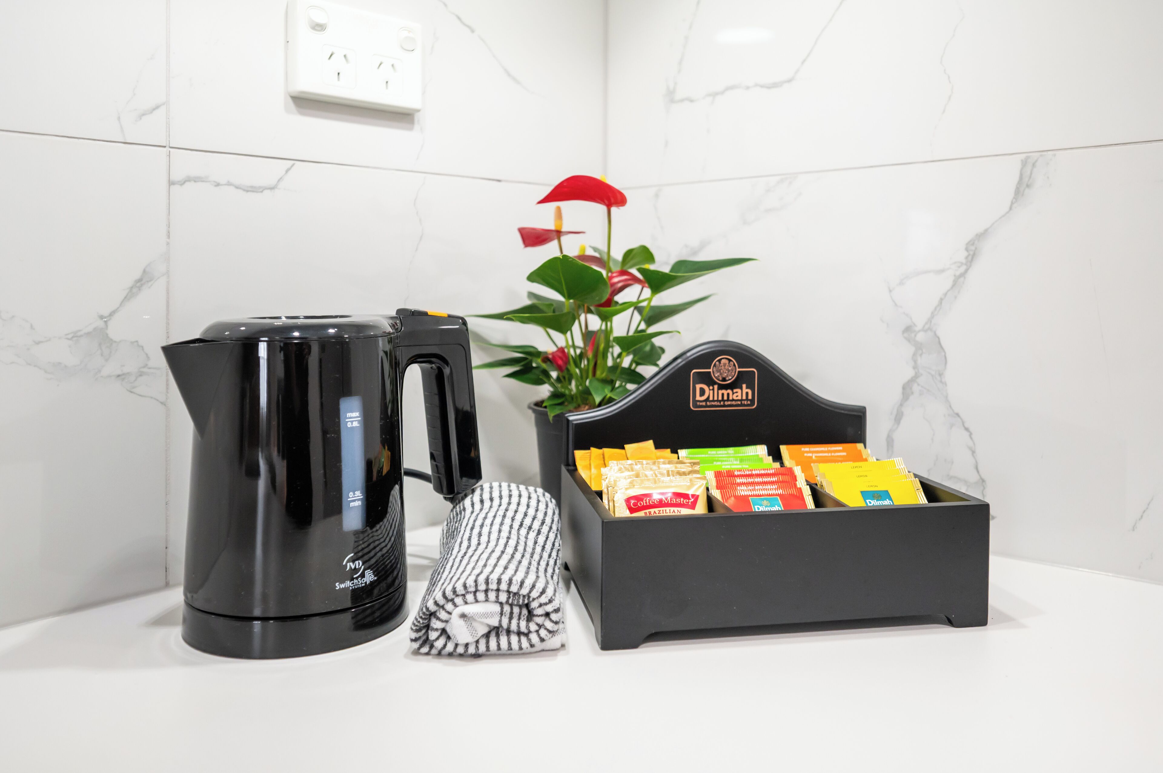 A coffee maker, a folded towel, and a box of coffee pods on a white countertop.