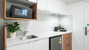 Una cocina moderna con armarios blancos, un lavamanos de acero inoxidable, un microondas y un lavavajillas.
