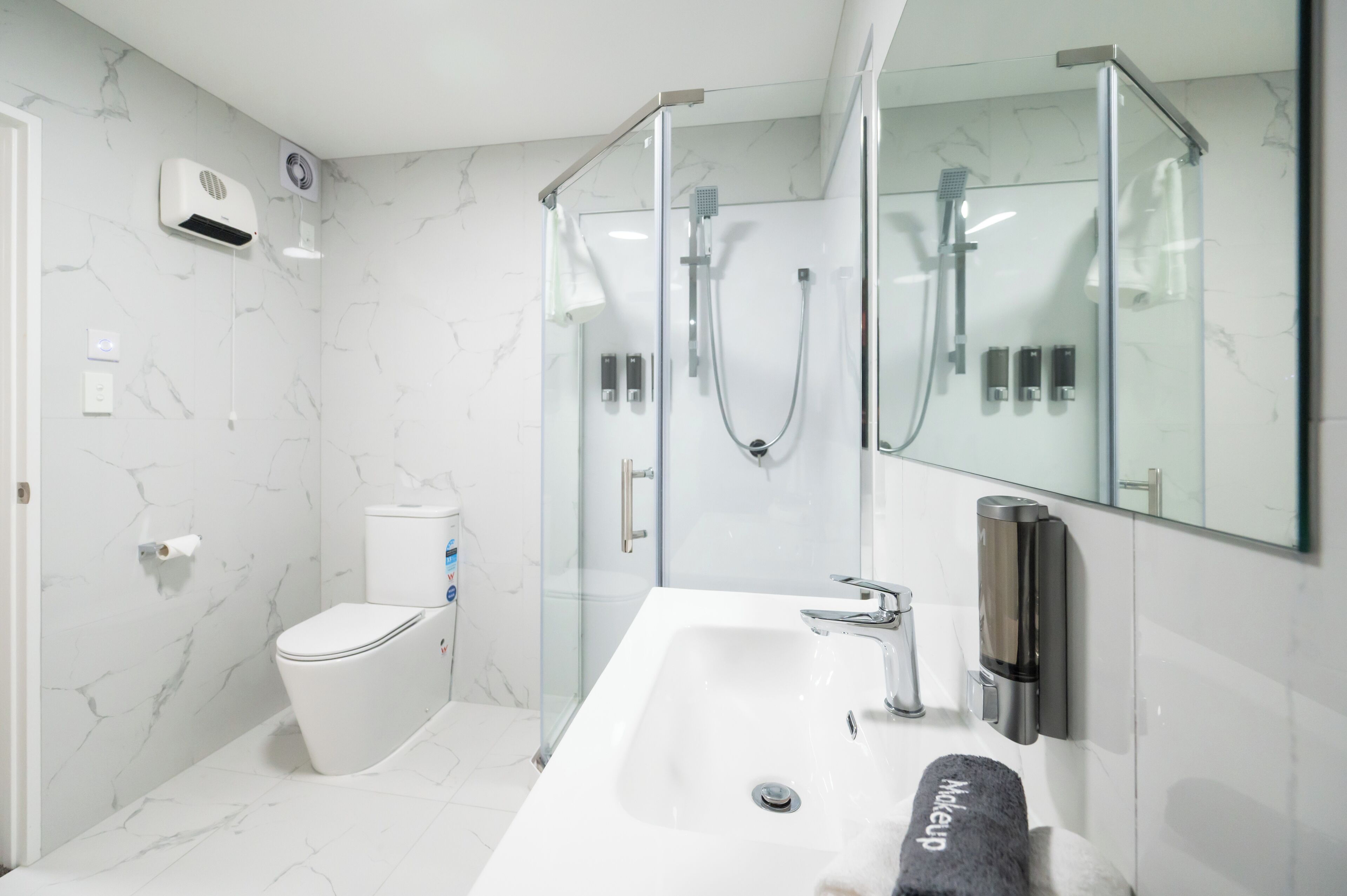 A modern bathroom with a glass-enclosed shower, a white sink, and a toilet.