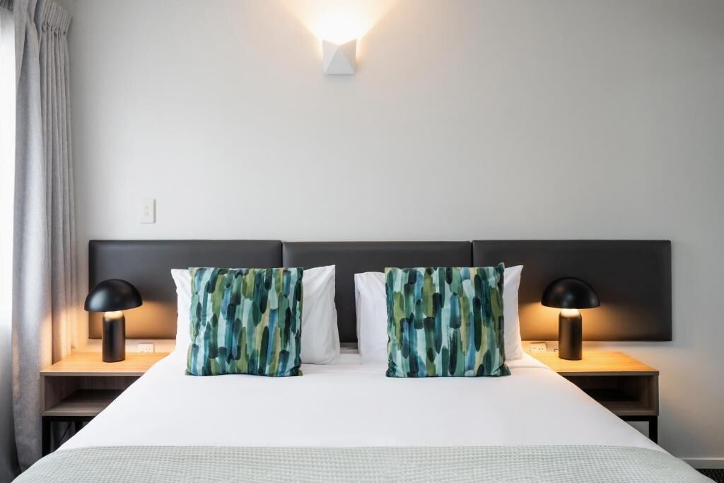 Ein Hotelzimmer mit einem großen Bett, zwei Nachttischlampen und einer Wandleuchte.