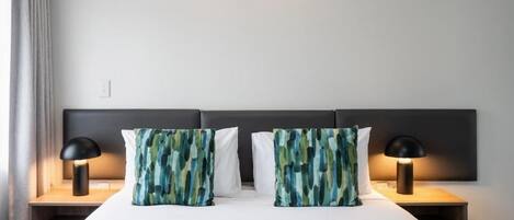 Ein Hotelzimmer mit einem großen Bett, zwei Nachttischlampen und einer Wandleuchte.