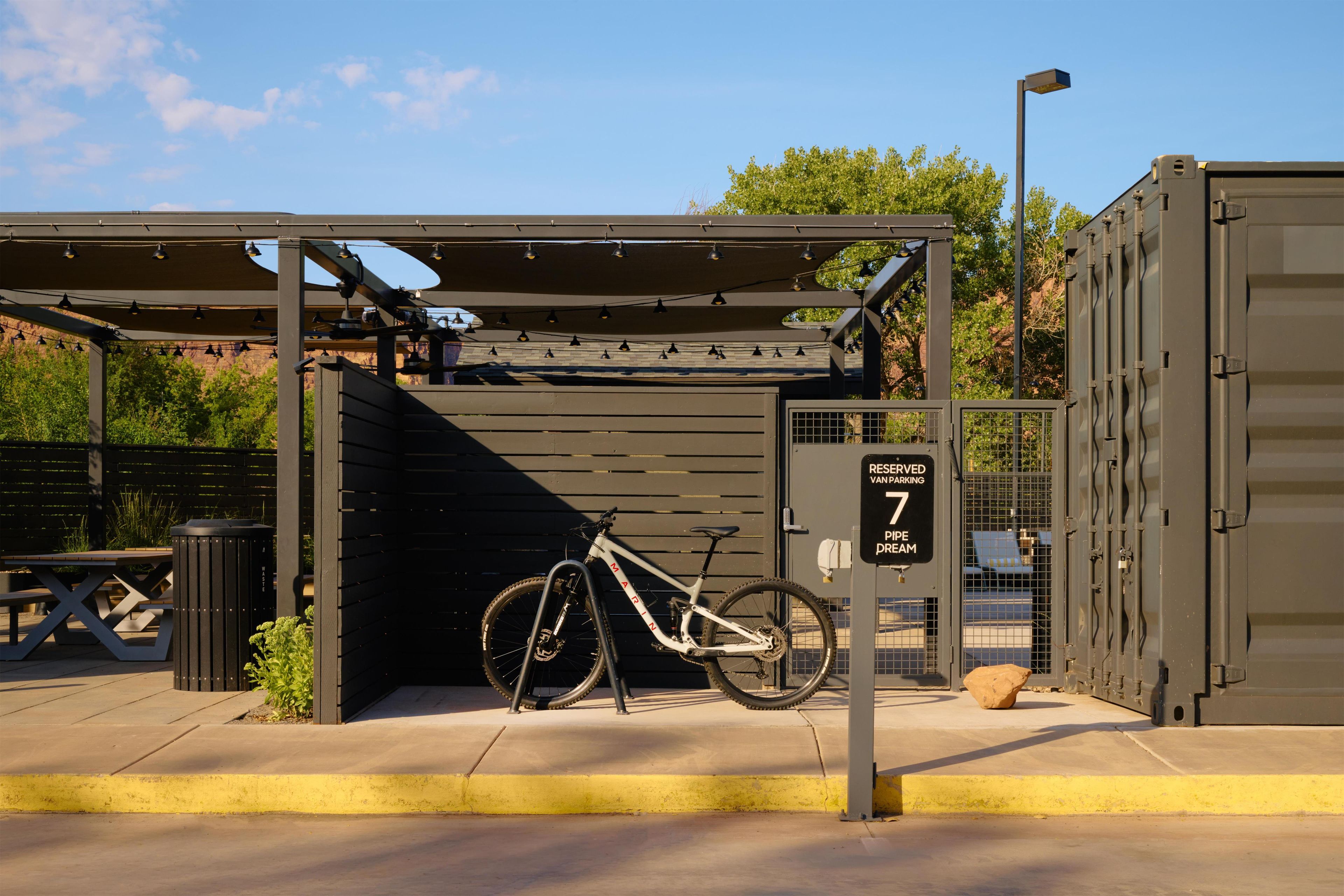 A bicycle parked under a covered bike rack with a sign indicating reserved parking.
