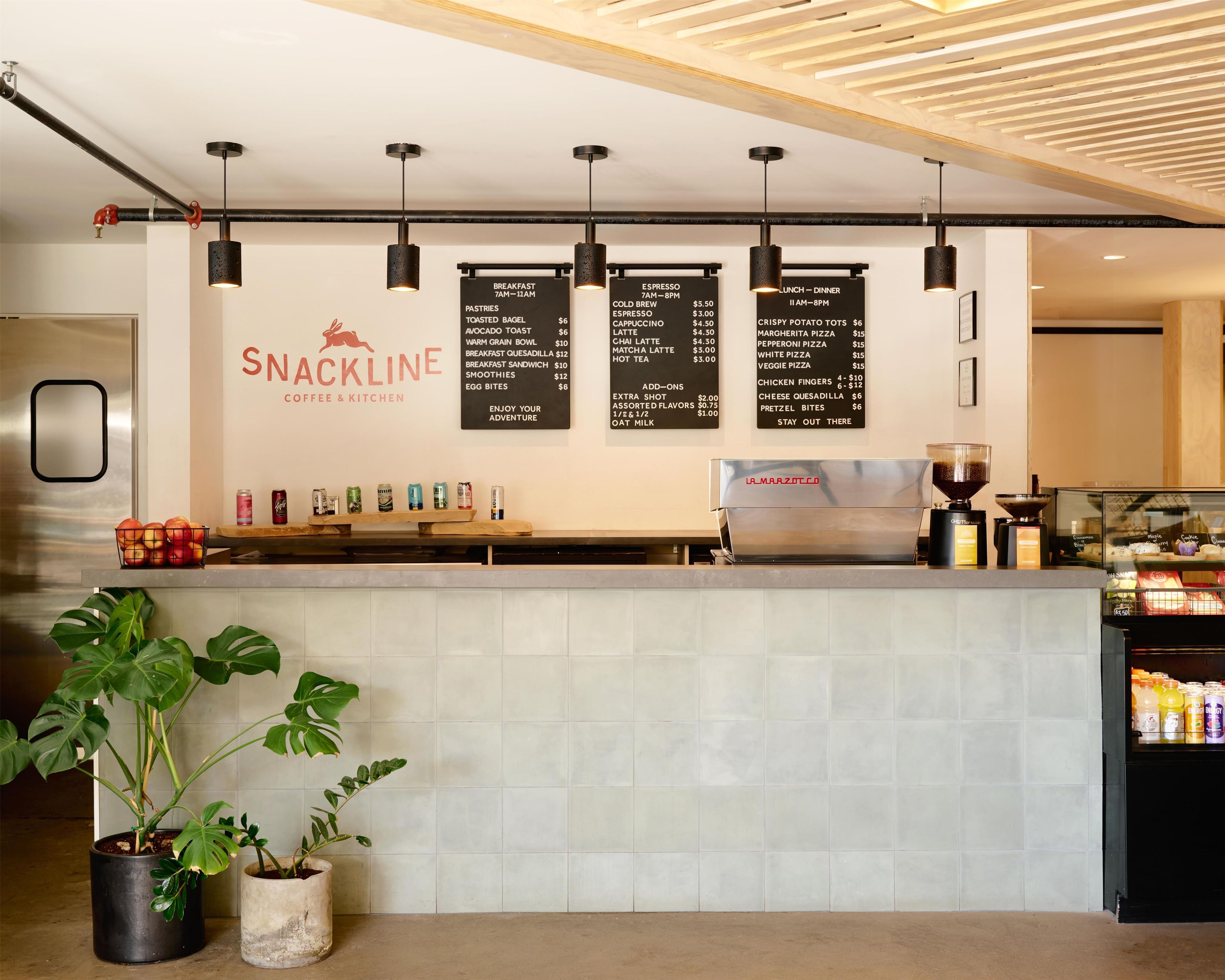 Un bar de aperitivos con un menú, una máquina de café y diversas bebidas.
