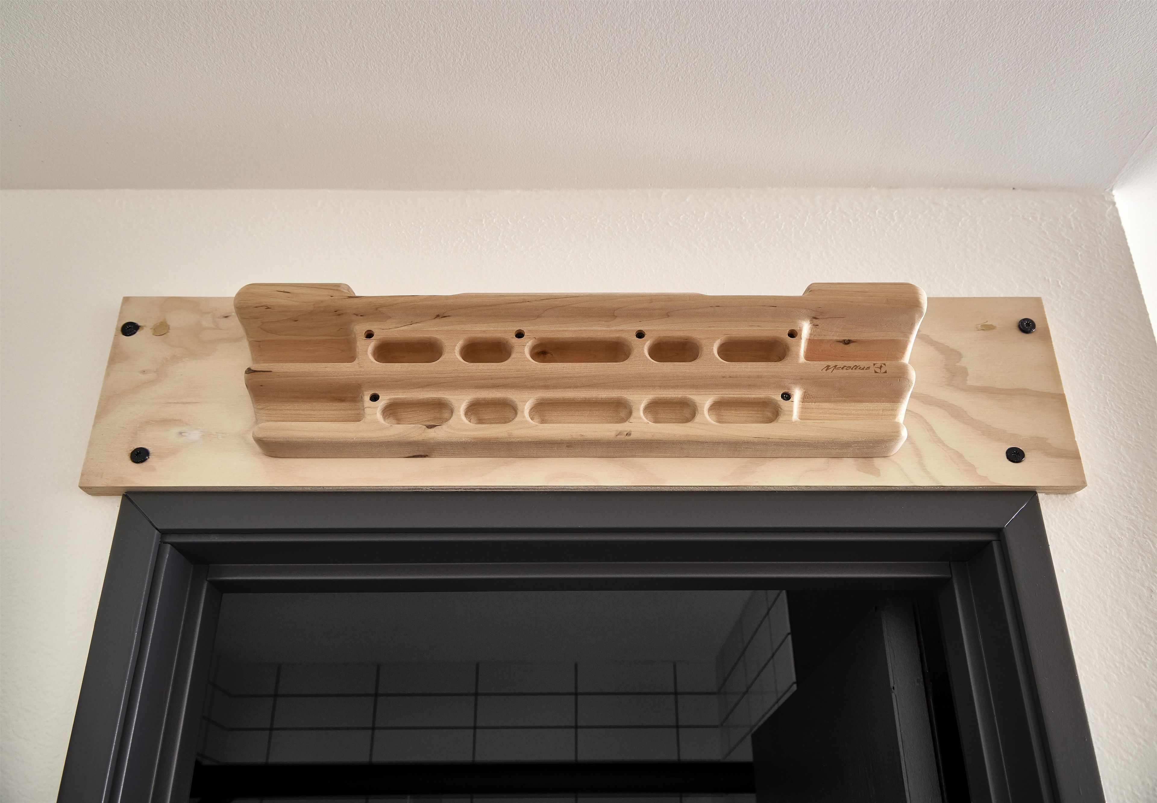 A wooden shelf with holes, mounted on a wall above a black-framed fireplace.