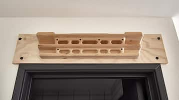 A wooden shelf with holes, mounted on a wall above a black-framed fireplace.