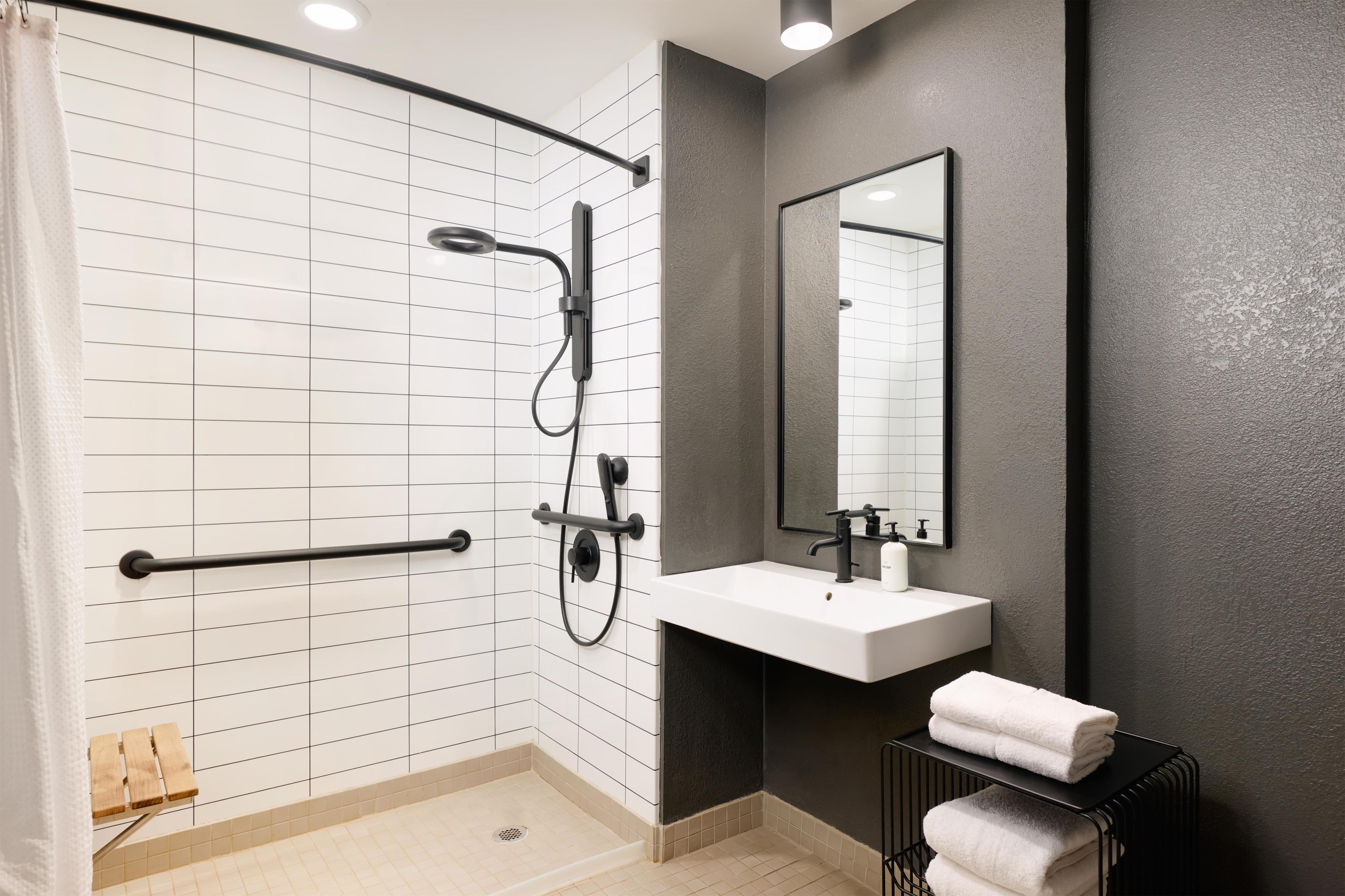 A modern bathroom with a walk-in shower, a white sink, and a large mirror.