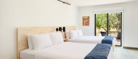 A hotel room with two beds, a large window, and a view of the outdoors.