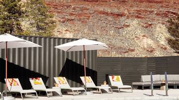 Een buitenzwembad, parasols bij het zwembad en ligstoelen