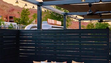 An outdoor seating area with a sofa and two small tables, a canopy overhead, and a sign reading 'DUST CLUB'.
