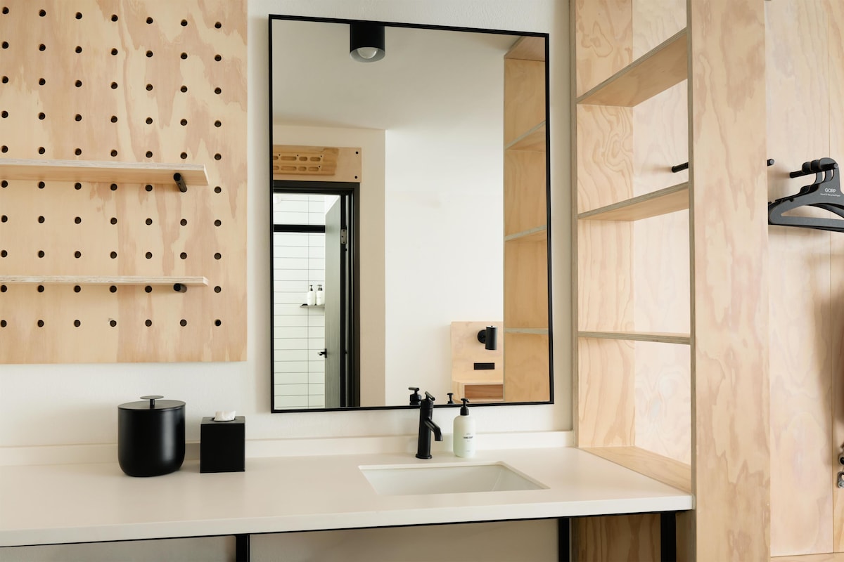 A modern bathroom with a large mirror, wooden wall paneling, and a white sink.
