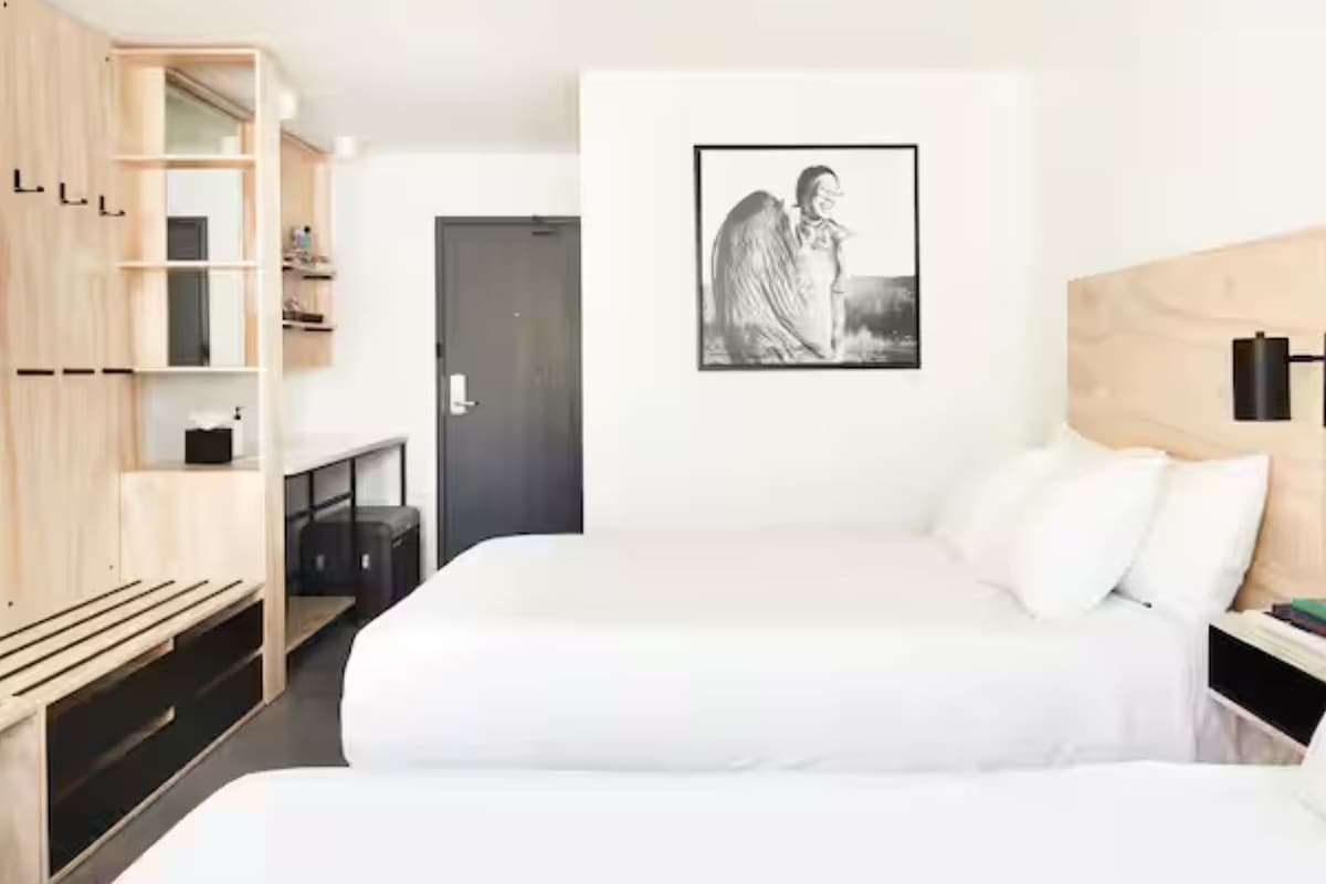 A hotel room with a bed, a wardrobe, a door, and a wall-mounted shelf.