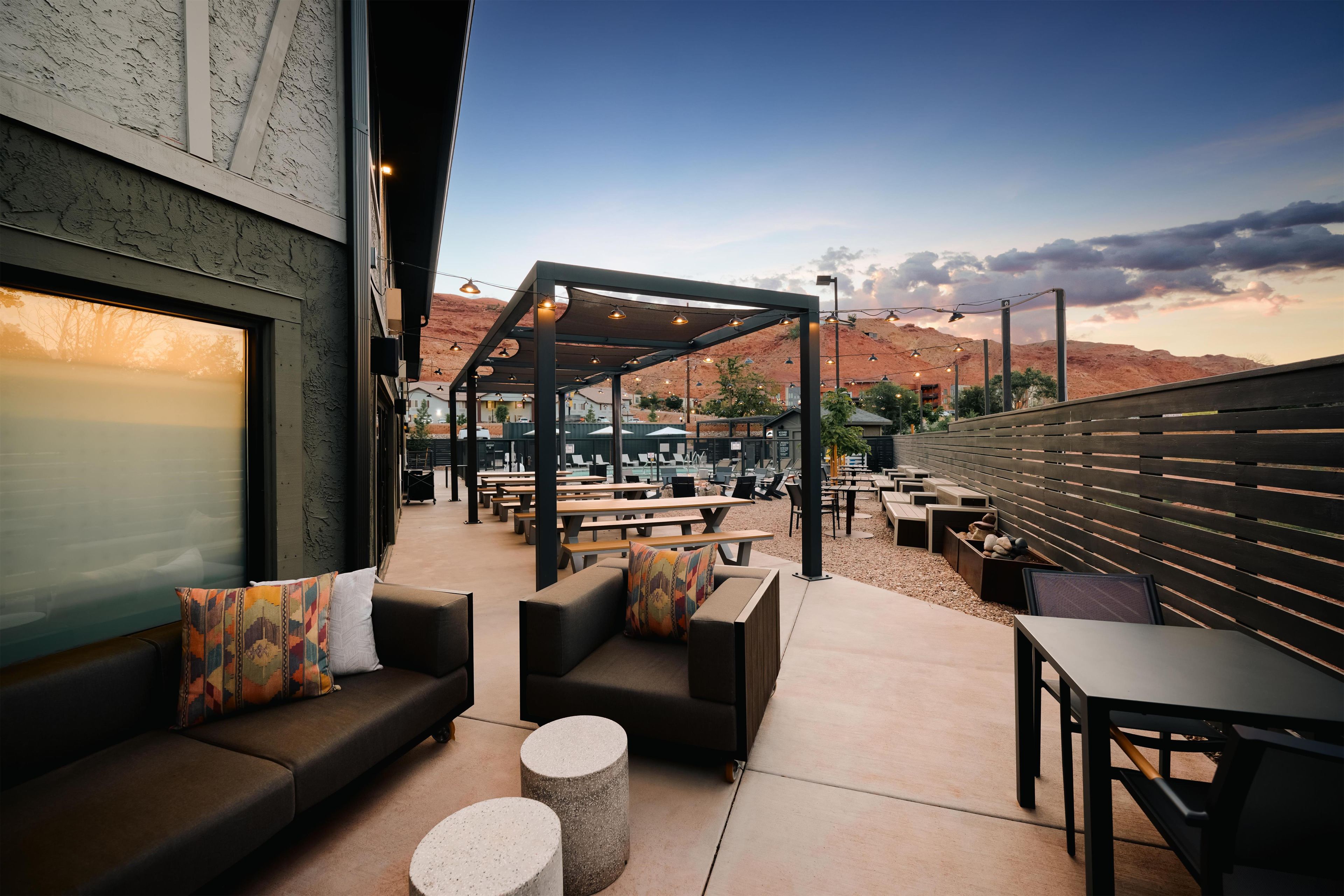 Un espace extérieur aménagé avec des tables et des chaises, un espace de repos couvert et une vue sur le paysage environnant.
