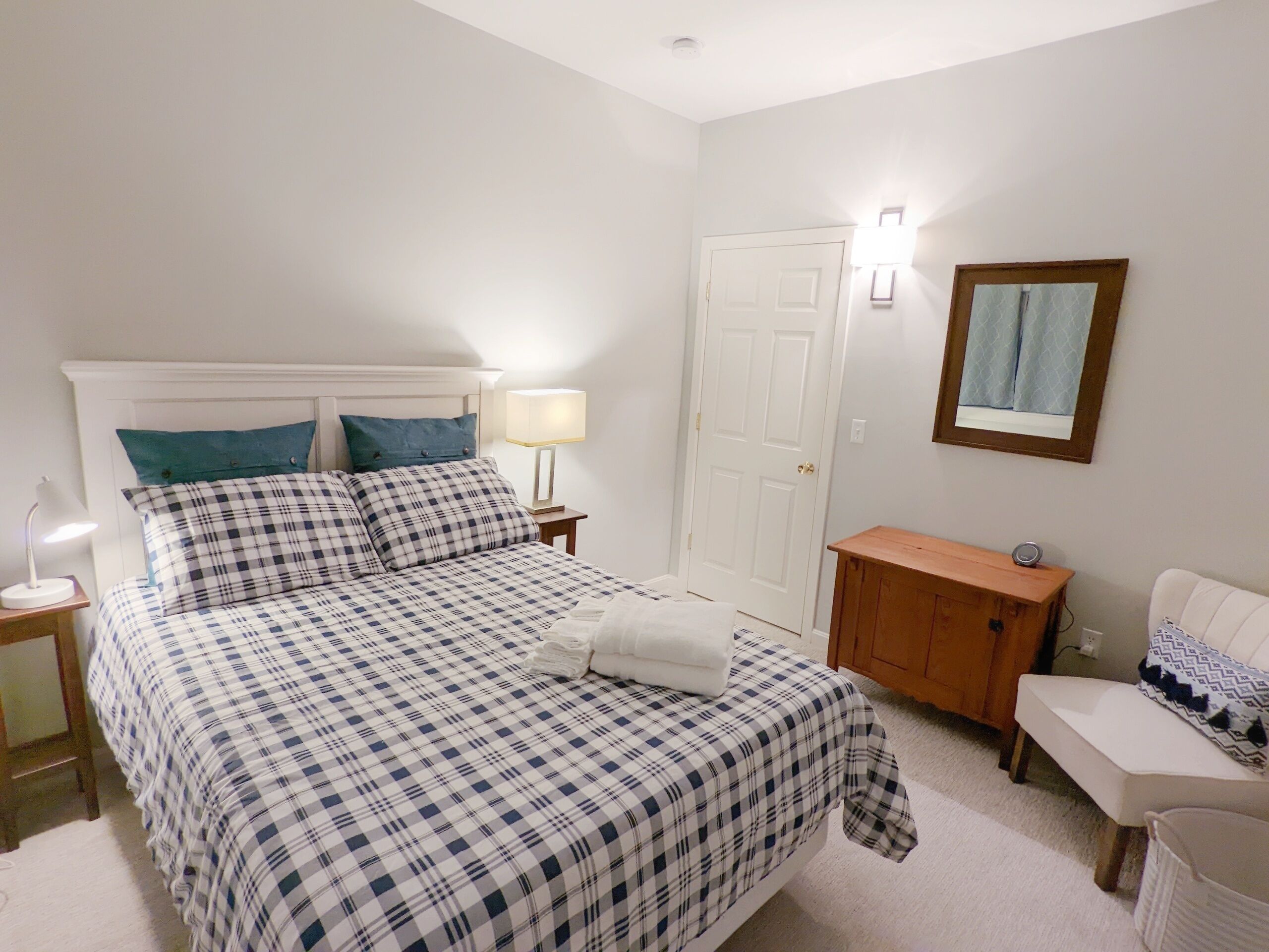 A bedroom with a bed, a nightstand, a bedside table, a dresser, and a chair.