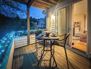 A wooden deck with a table and chairs, a bottle of wine, and a bowl.