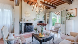 A cozy living room with a fireplace, a chandelier, and comfortable seating. - Cicale Farmhouse 3 Bedrooms Farmhouse With Pool (Lucca)