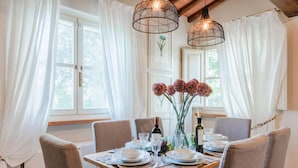 A dining table set for four with chairs, a vase with flowers, and a bottle of wine. - Cicale Farmhouse 3 Bedrooms Farmhouse With Pool (Lucca)
