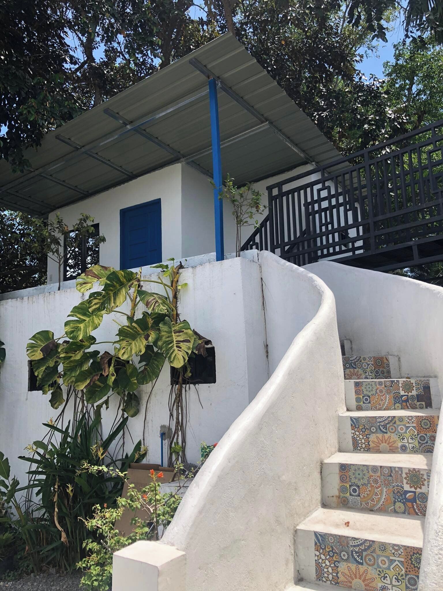 A curved staircase with colorful tiles leading to a covered area with a blue door.