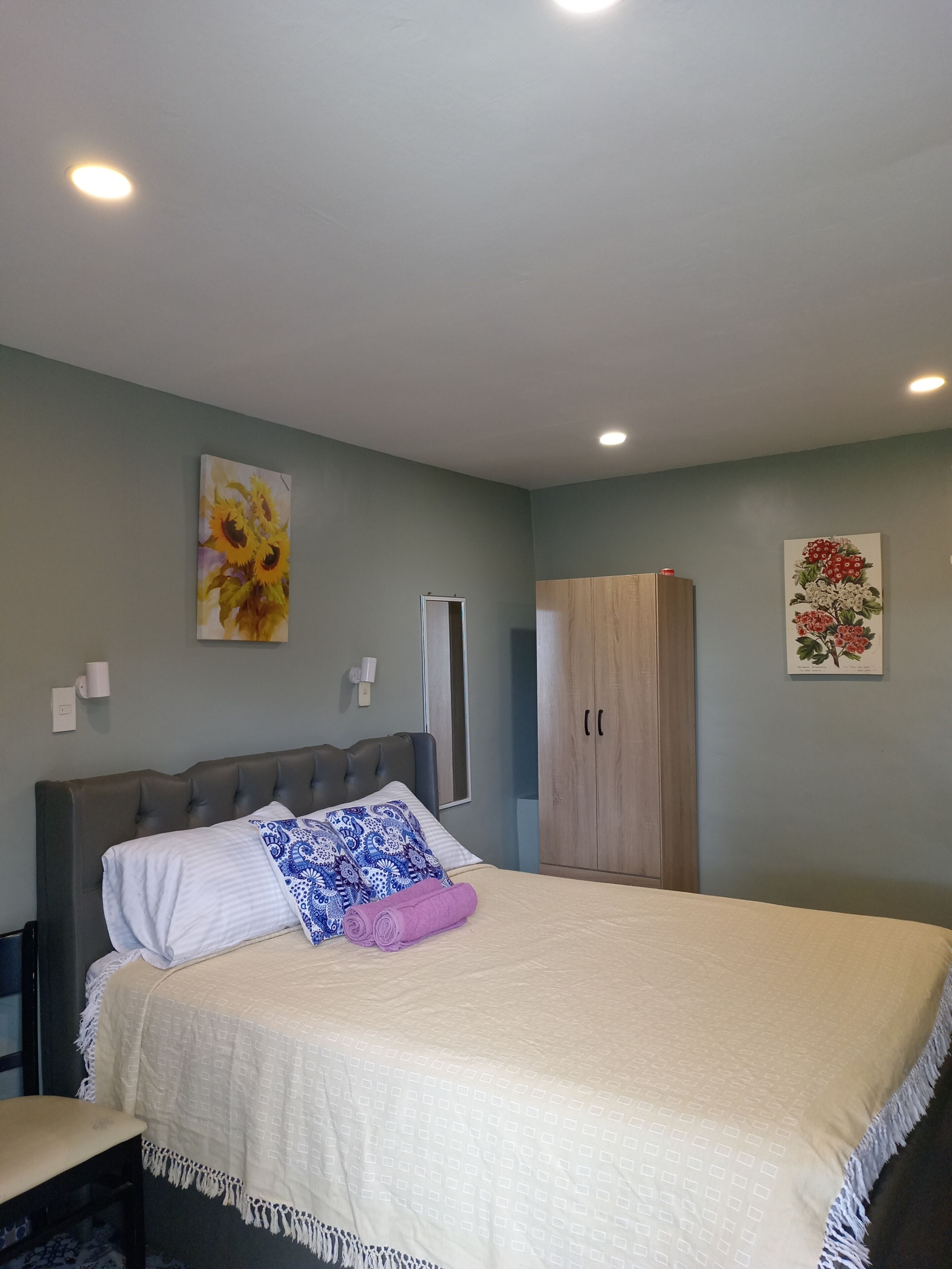 A bedroom with a bed, a wardrobe, and two wall-mounted light fixtures.