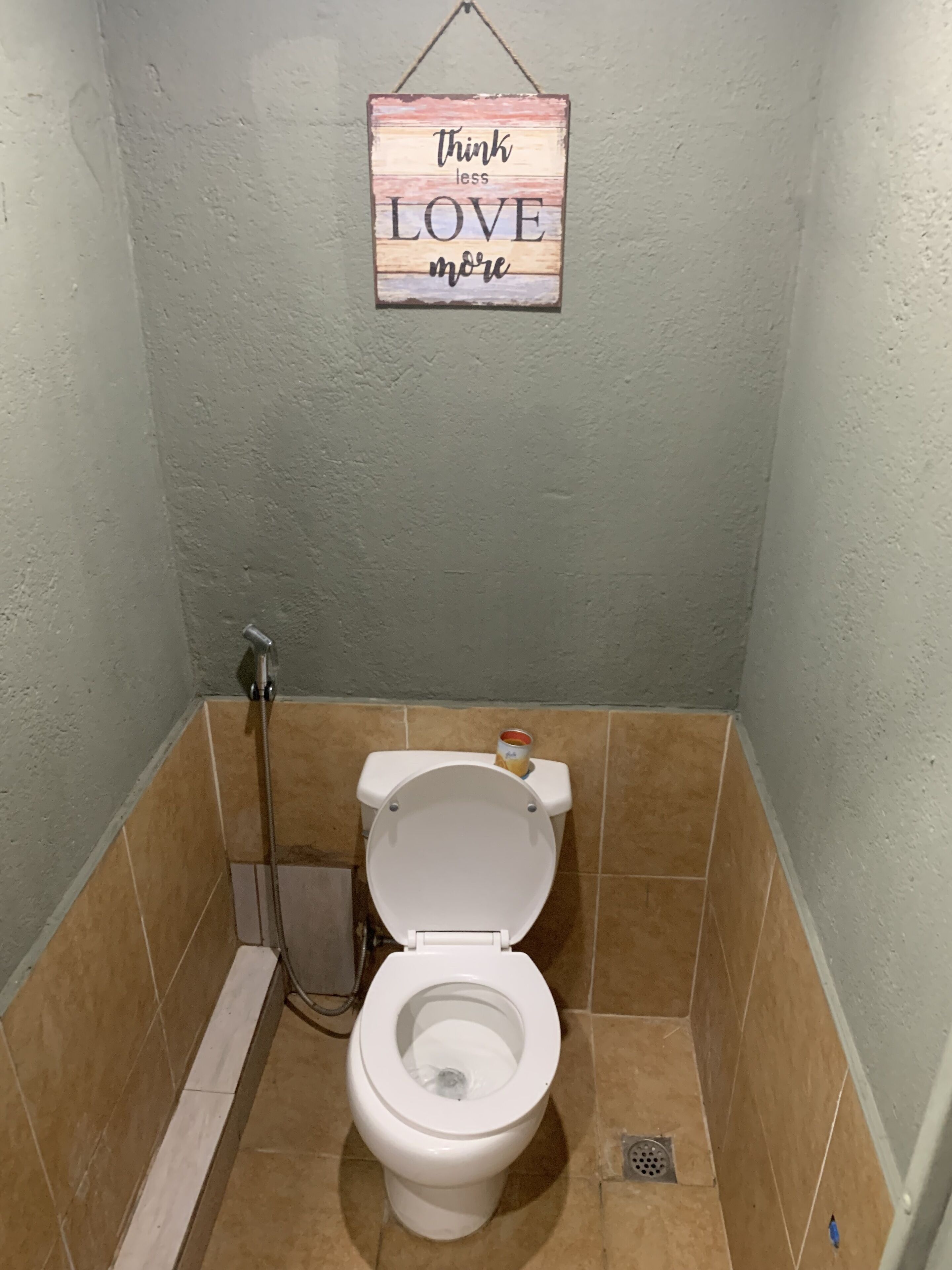 Ein Badezimmer mit Toilette, Dusche und einem Schild mit der Aufschrift 'think less love more'.