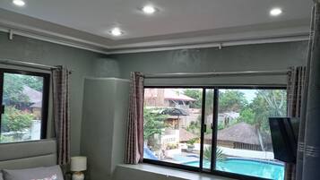 A bedroom with a bed, a window, a TV, and a small table.