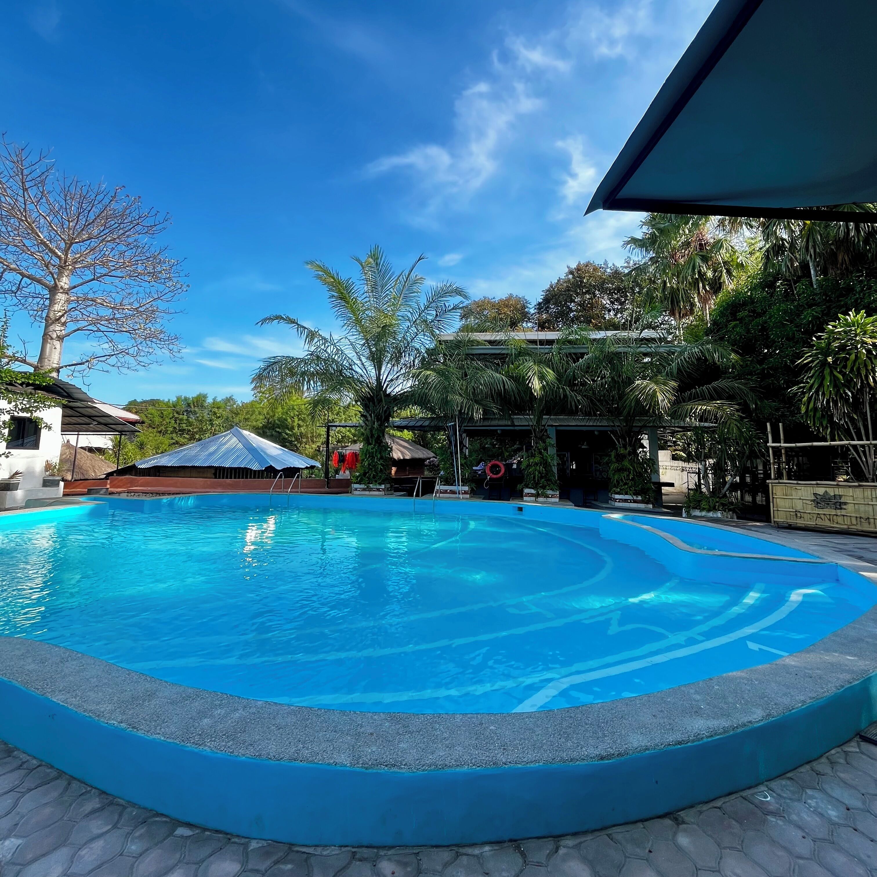 Una piscina con superficie de agua azul cristalina, rodeada por una solana de piedra.