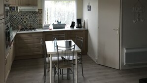 Eine kompakte Küche mit Essbereich, ausgestattet mit Holdelementen, einem Gasherd, einer Kaffeemaschine und Pendelleuchten.