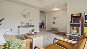 A living room with a sofa, coffee table, and a small side table with a plant. There is a wall-mounted mirror and a ceiling light fixture. - Charming white picket fenced home in quiet area (Medford)