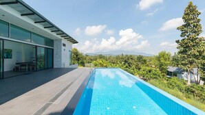 Una casa moderna con piscina, ventanas amplias y vistas a las montañas.