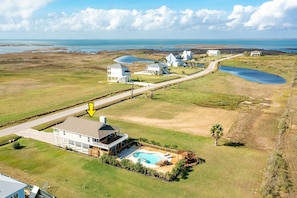 An aerial view of a coastal property with a swimming pool, a large house with a deck, and a smaller building. - Dog-friendly house with private pool, spacious deck, central AC, & washer/dryer (Galveston)